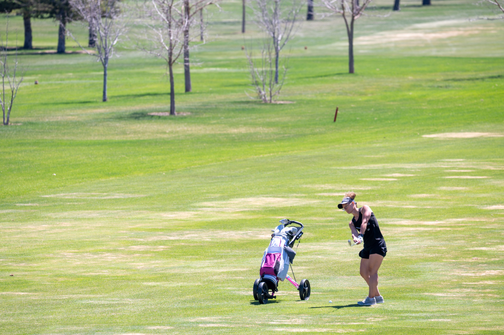 Patron swinging her clubs on the golf course